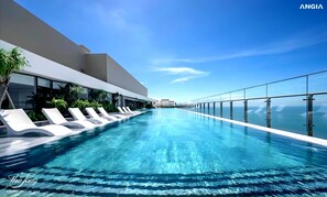 Ein moderner Infinity-Pool mit klarem, blauem Wasser, umgeben von weißen Liegestühlen und Glasgeländern, mit Blick auf eine malerische Meereslandschaft.