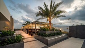 A modern outdoor seating area with a palm tree, benches, and planters. - The Song Vung Tau Apartment Cookies (Ho Chi Minh City)