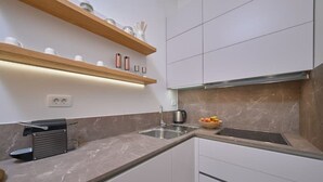 A modern kitchen with a marble countertop, a built-in sink, and a kettle. - Salve Luxury Apartment by Litto (Split)