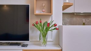 A modern kitchen with a TV, a wooden cabinet, and a vase with red tulips. - Salve Luxury Apartment by Litto (Split)