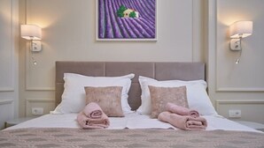 A neatly made bed with two pillows and folded towels, a headboard, and wall-mounted lamps. - Salve Luxury Apartment by Litto (Split)