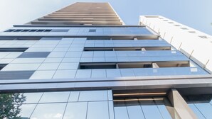 A modern high-rise building with a reflective glass facade and a series of rectangular windows. - 360 VN On Lorena (São Paulo)