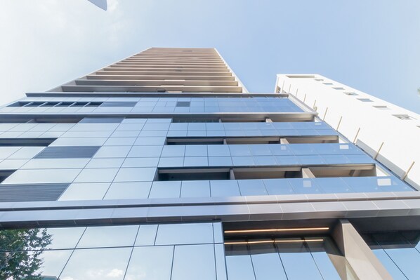 A modern high-rise building with a reflective glass facade and a series of rectangular windows. - 360 VN On Lorena (São Paulo)