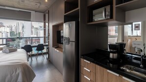 A modern hotel room with a balcony, a bed, a kitchenette, and a city view. - 360 VN On Lorena (São Paulo)