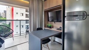 A modern kitchen with a stainless steel refrigerator, a flat-screen TV mounted above the counter, and a dining area with a table and chairs. - 360 VN On Lorena (São Paulo)