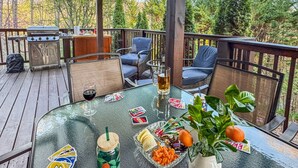 En terrasse med udendørs møbler, grill og et bord dækket til et måltid med snacks og drikkevarer.