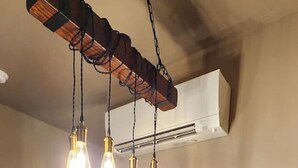 A kitchen with a marble countertop, wooden cabinets, and a hanging light fixture with exposed bulbs. - Nugget Suite - Main Street (Deadwood)