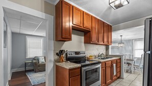 A modern kitchen with wooden cabinets, a stainless steel stove, and a tiled backsplash. - The Teal Door is a 3 Bedroom 1 Bath Unit. Sleeps 6. Linens Included! (Carolina Beach)