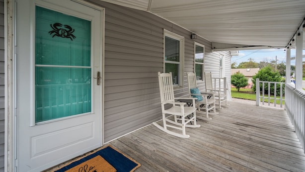 A covered porch with white rocking chairs and a glass door with a crab decal. - The Teal Door is a 3 Bedroom 1 Bath Unit. Sleeps 6. Linens Included! (Carolina Beach)