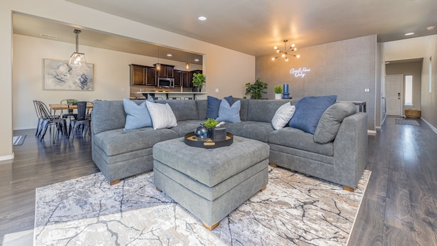 A modern living room with a sectional sofa, ottoman, and a dining area with chairs and a table.
