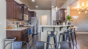 A modern kitchen with dark wood cabinets, stainless steel appliances, and a central island with bar stools.