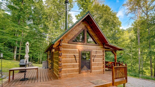 A wooden cabin with a deck, a covered porch, and a chimney. - Cozy Log Cabin on 11 Acres: 3 Mi to Cherokee Lake! (Bean Station)