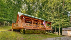 A wooden cabin with a porch, a flag, and a small attached structure. - Cozy Log Cabin on 11 Acres: 3 Mi to Cherokee Lake! (Bean Station)