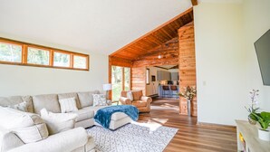 A spacious living area with a large sofa, a coffee table, and a wooden ceiling.