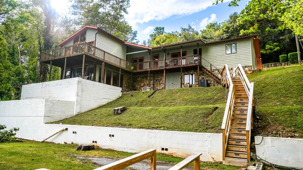 A two-story house with a balcony, a stone foundation, and a wooden staircase leading up to the entrance. - Lakeview Landing, pet friendly lake front home on Boone Lake (Kingsport)