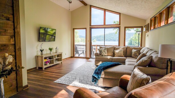 A spacious living room with a large window, a sofa, a coffee table, and a wooden console table with decorative items.