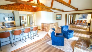 A spacious kitchen with modern appliances, a bar area with stools, and a dining area with wooden furniture.