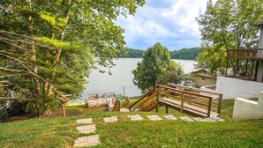 A wooden deck with a staircase leading to a viewing platform overlooking a lake.