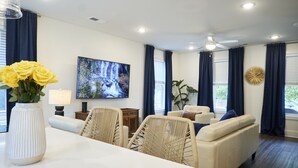 Een moderne woonkamer met een witte bank, een eettafel en een televisie.