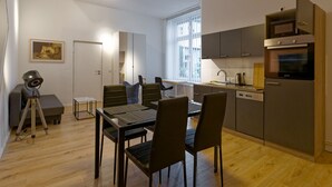 Una cucina moderna con zona pranzo, pavimento in legno e un treppiede nell'angolo.
