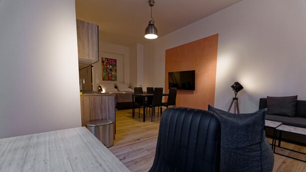 Un soggiorno moderno con zona pranzo, divano, tavolino e TV a parete.