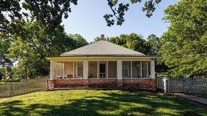 A single-story house with a covered porch, brick foundation, and a fenced yard. - Relaxing Home on the Outskirts! (Independence)