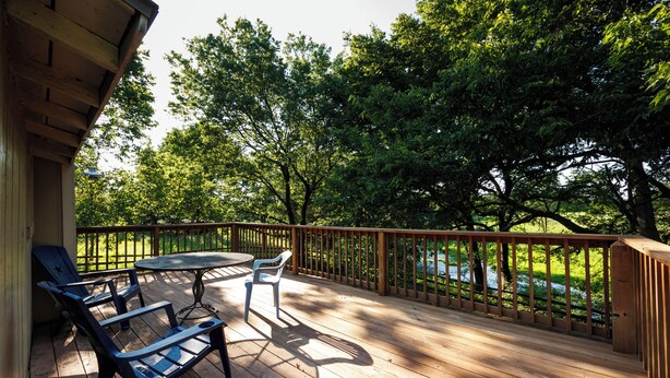 A wooden deck with a table and chairs, surrounded by a wooden railing and trees. - Relaxing Home on the Outskirts! (Independence)