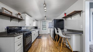 A kitchen with white cabinets, a black stove, and a wooden floor. - Relaxing Home on the Outskirts! (Independence)