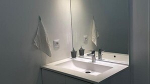 Ett modernt badrum med en vit tvättställ, en spegel och en handduk som hänger på väggen.
