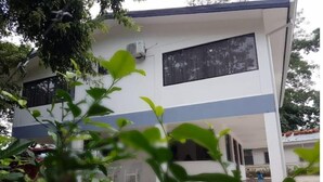 Un edificio moderno de dos pisos con techo plano, ventanas amplias y una unidad de aire acondicionado visible.