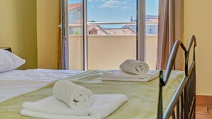 Een hotelkamer met een bed, een raam met uitzicht op gebouwen, en een stoel.