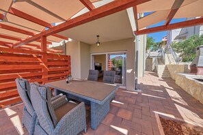 Eine Außenpatio mit Tisch und Stühlen, einer Holzpergola und einer Steinmauer.