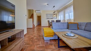 Een moderne woonkamer met een flatscreen televisie, een houten salontafel, een bank en een trap naar een hoger gelegen verdieping.