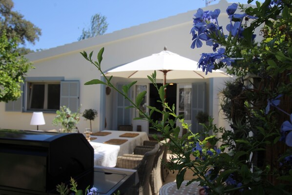 Relax in the shaded outdoor seating area, complete with a grill and wicker furniture.