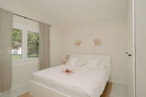 A bedroom with a bed, curtains, a bedside table, a lamp, and a wall-mounted light fixture.