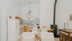A modern living room with a dining area, white furniture, a fireplace, and a kitchen in the background. - Casa Familia - House for 4 (Sa Pobla)