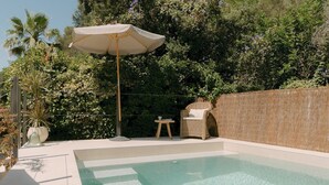 A swimming pool with a sun umbrella, a wicker chair, and a small table. - Casa Familia - House for 4 (Sa Pobla)