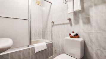 A bathroom with a toilet, a shower, and a sink.