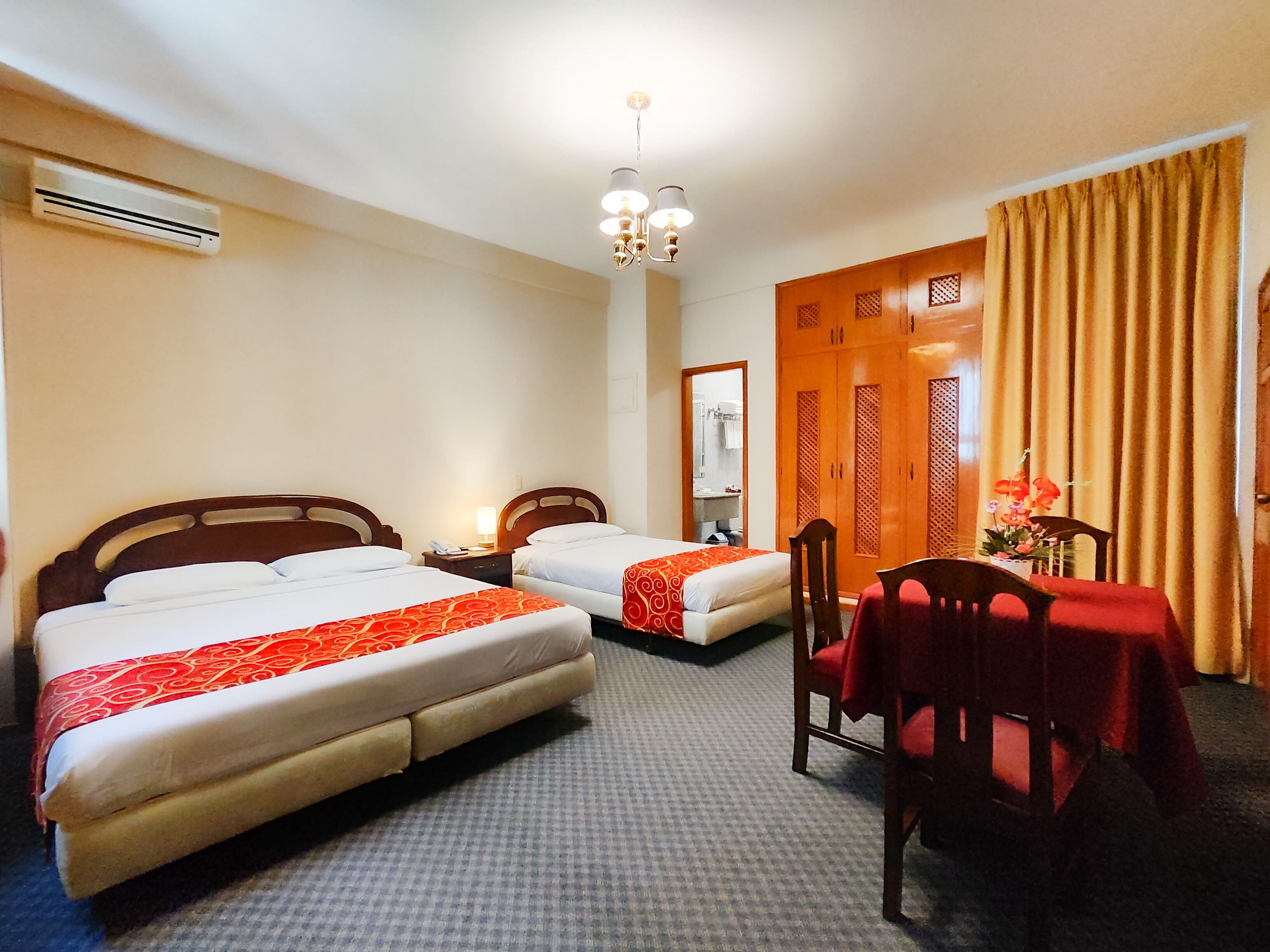 Een hotelkamer met twee bedden, een bureau met stoel, een spiegel en een kledingkast.