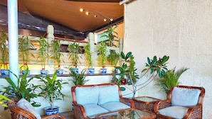 Wicker furniture with cushions, potted plants, and a ceiling with lights. - Lido Hotel (Santa Cruz)