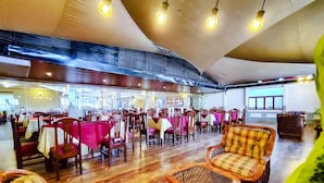 A spacious restaurant with wooden flooring, tables with red and white tablecloths, and wicker chairs. - Lido Hotel (Santa Cruz)