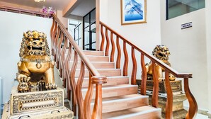 A staircase with ornate lion statues at the base, a chandelier, and a framed artwork on the wall. - Lido Hotel (Santa Cruz)