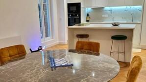 A modern kitchen with white cabinets, a black microwave, and a marble countertop. - Bel Appartement Avec Parking au Coeur de Reims (Reims)