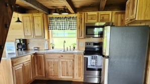 A rustic kitchen with wooden cabinets, a stainless steel refrigerator, and a built-in oven.