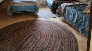 An attic bedroom with two beds, a window with curtains, a small table, and a hanging light fixture.