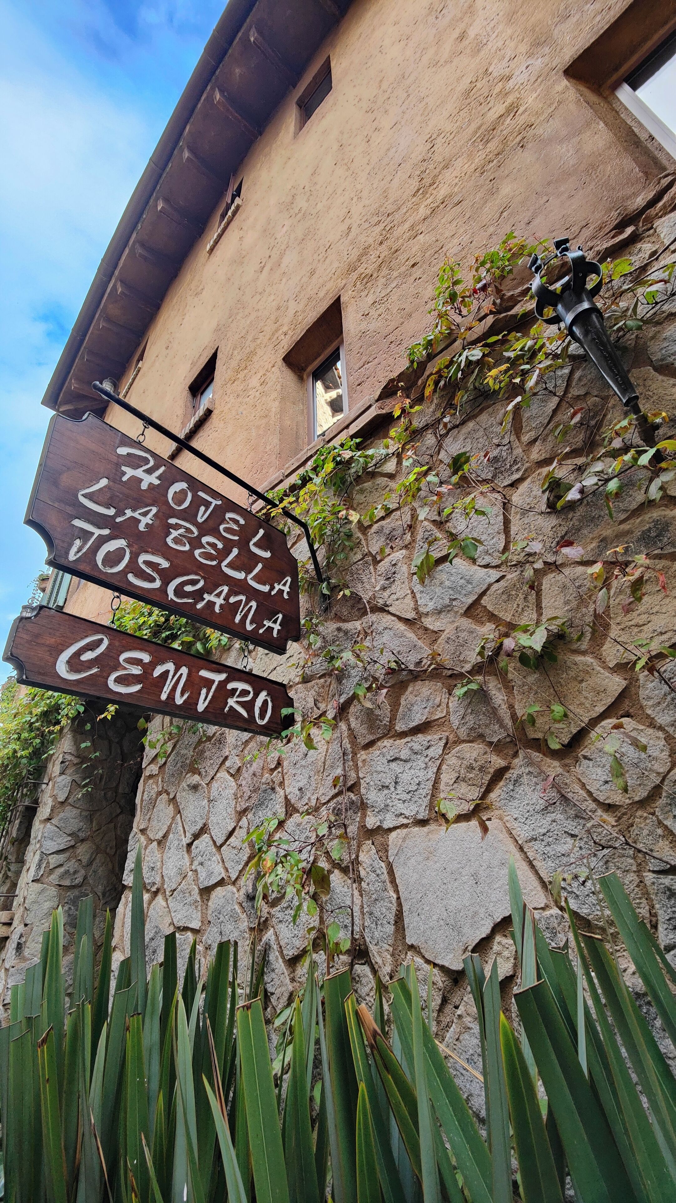 A stone building with a sign that reads "Hotel La Scala Joscanla Centro".