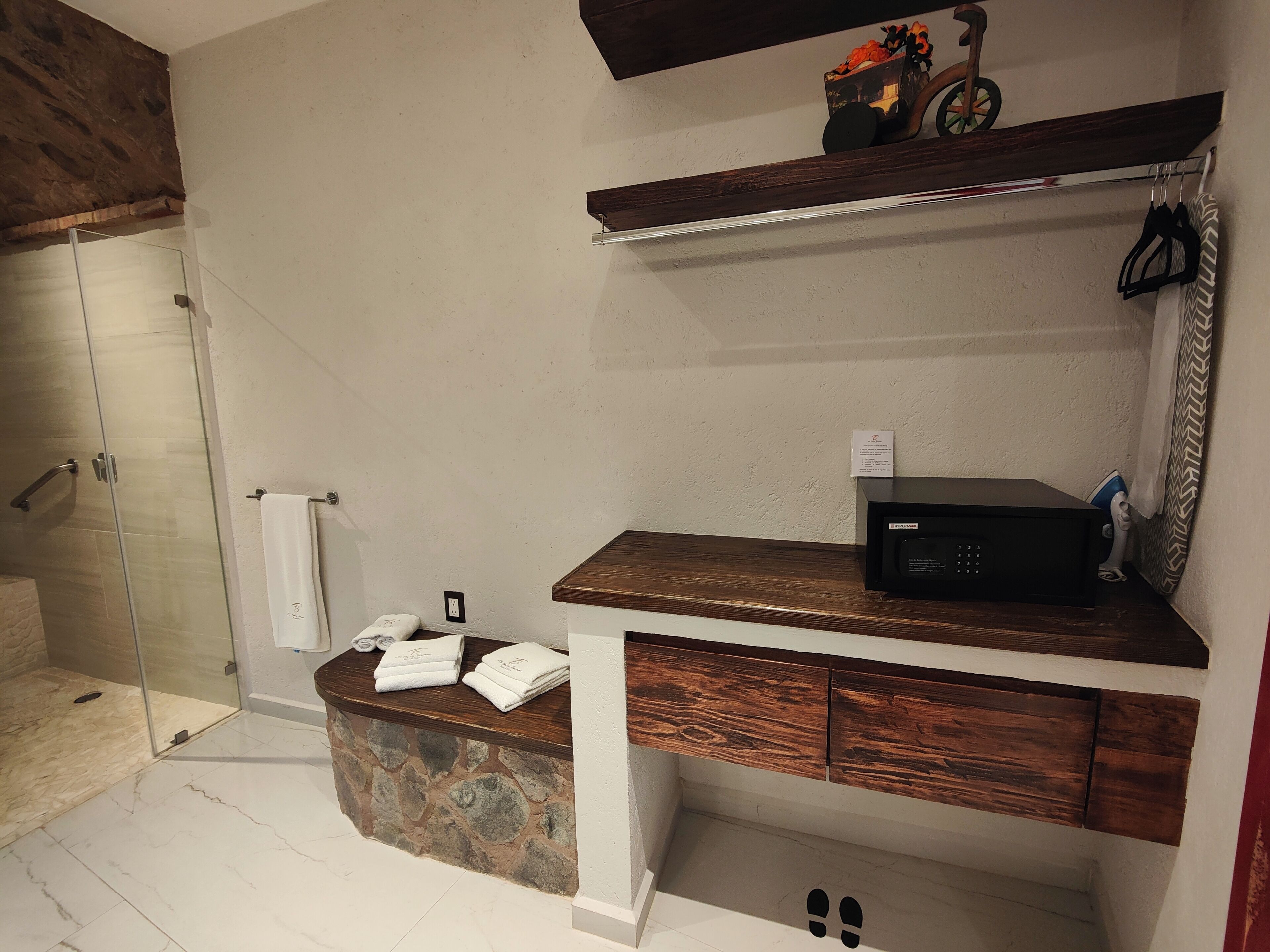 Un baño con encimera de piedra, tocador de madera, microondas y toallero.