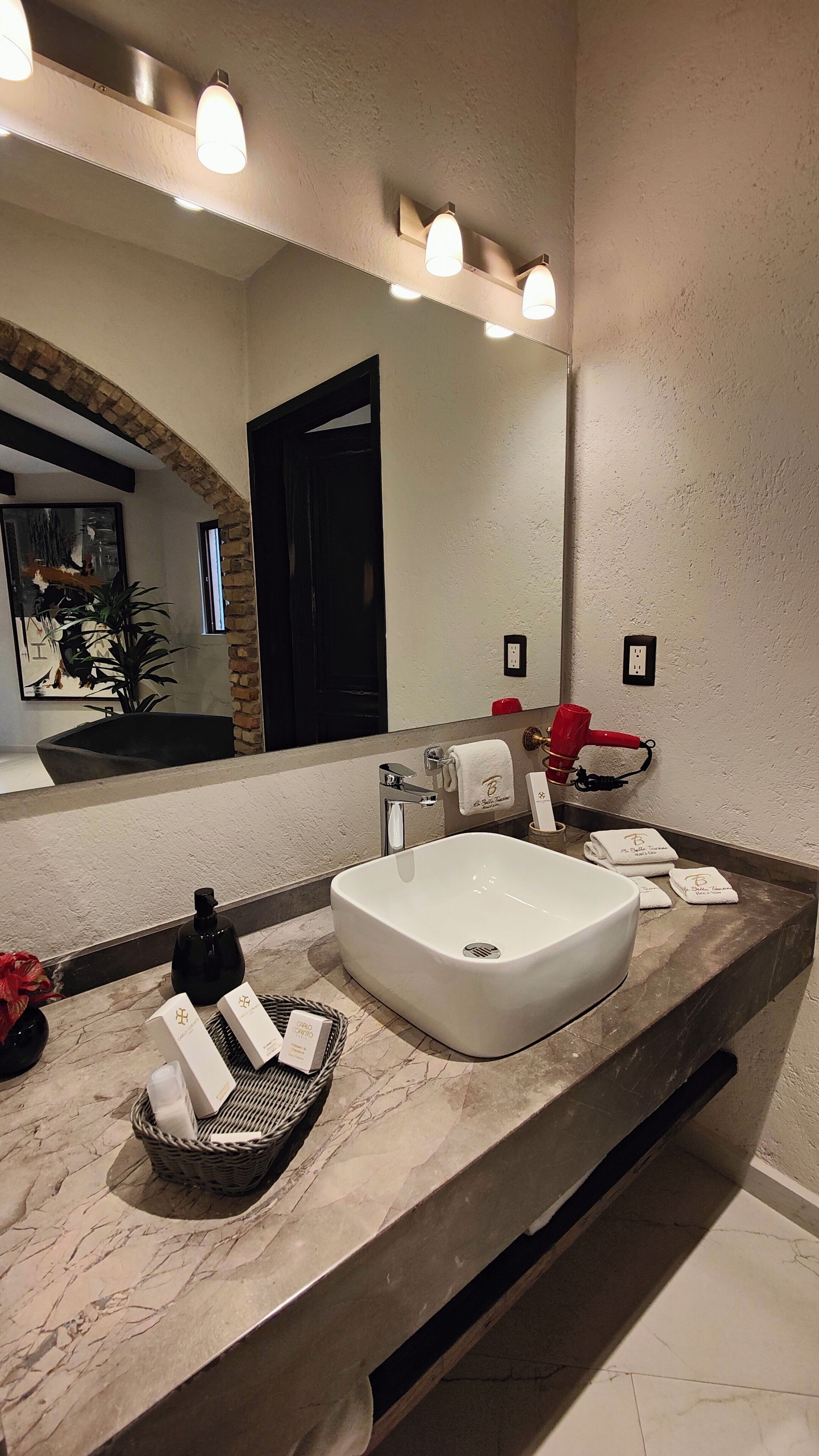 Un bagno moderno con un lavandino ampio, uno specchio e un portasciugamani.