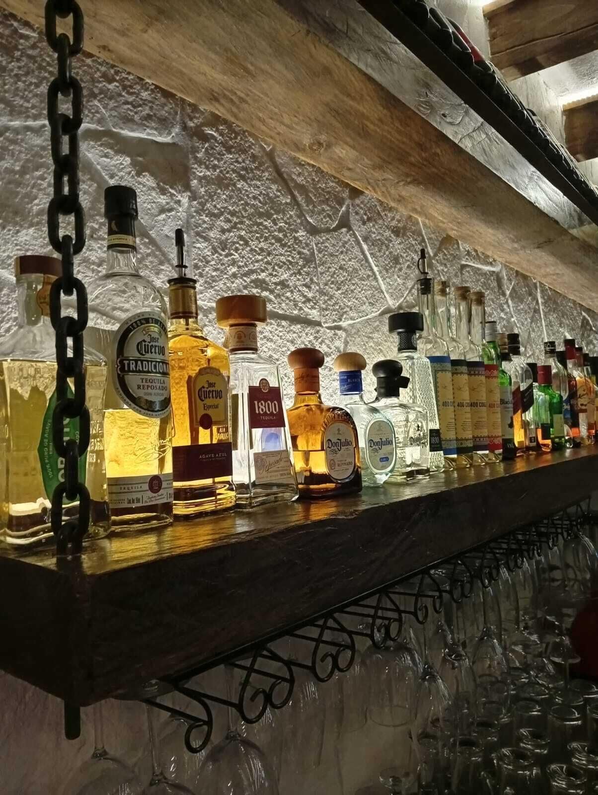 Un bar con una variedad de botellas de licor y vasos.