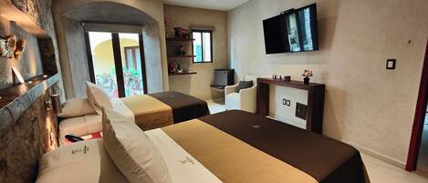 A hotel room with two beds, a TV, a fireplace, and a stone wall.